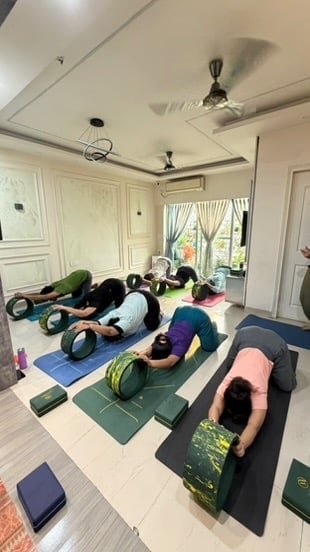Yoga group performing Uttana Shishosana (Extended Puppy Pose) under instructor guidance
